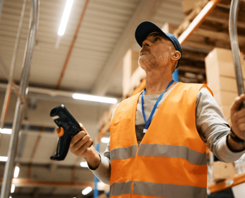 Warehouse employee using a barcode scanner to manage inventory with a Warehouse Management System (WMS)